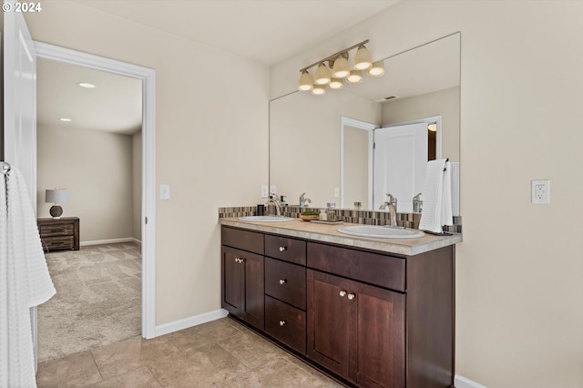 full bath with double vanity, baseboards, and a sink