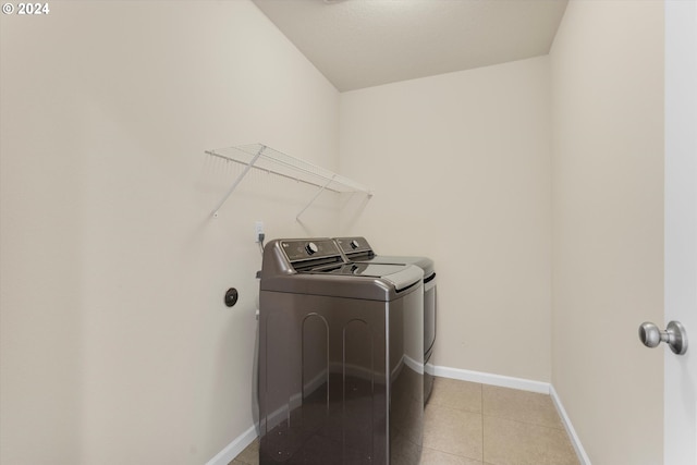 laundry area featuring light tile patterned floors, baseboards, laundry area, and washing machine and clothes dryer