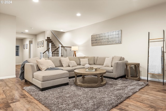 living area with recessed lighting, baseboards, wood finished floors, and stairs