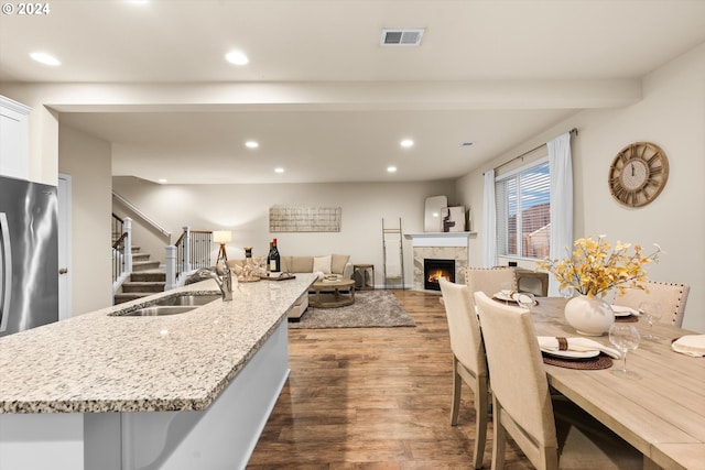 kitchen with a sink, recessed lighting, dark wood-style flooring, and a tiled fireplace