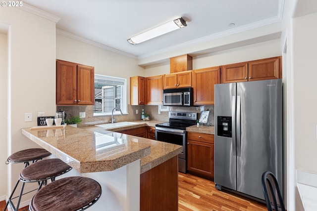 kitchen featuring a kitchen bar, a sink, backsplash, tile countertops, and appliances with stainless steel finishes