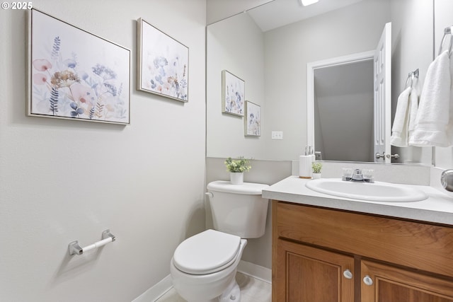 half bath with toilet, vanity, and baseboards