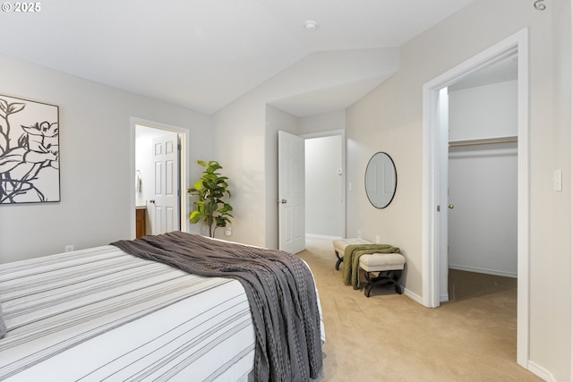 bedroom with baseboards, vaulted ceiling, a closet, a walk in closet, and light colored carpet