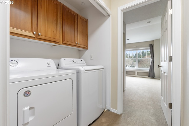 laundry room with cabinet space, light colored carpet, baseboards, and washing machine and clothes dryer