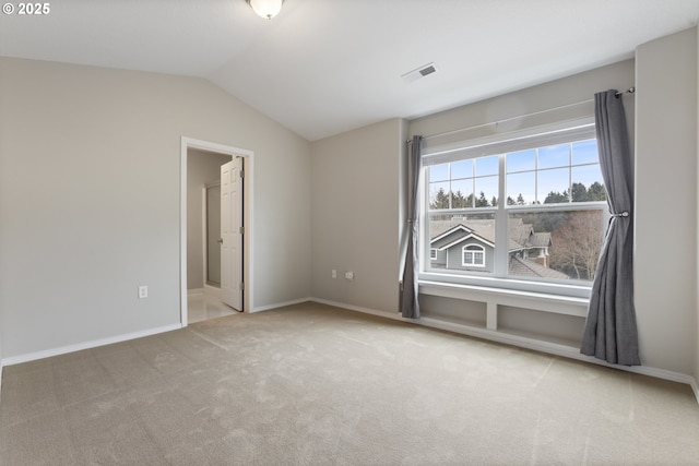 spare room featuring carpet flooring, baseboards, visible vents, and vaulted ceiling