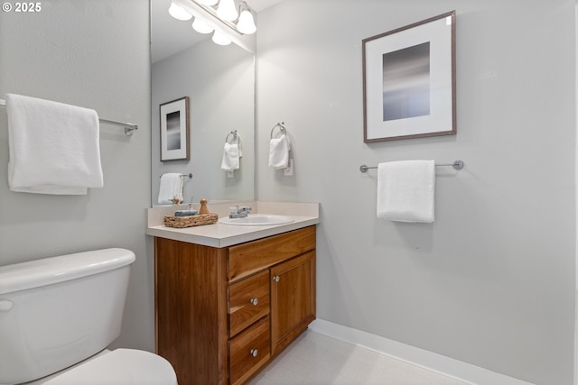 bathroom featuring baseboards, toilet, and vanity