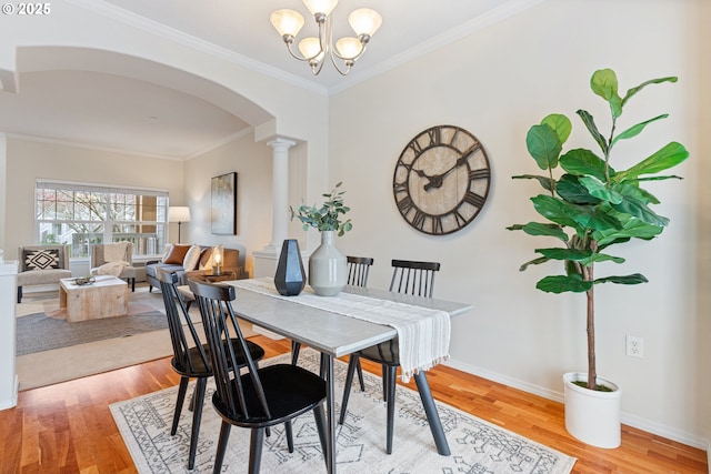 dining area with an inviting chandelier, light wood-style flooring, arched walkways, and ornate columns