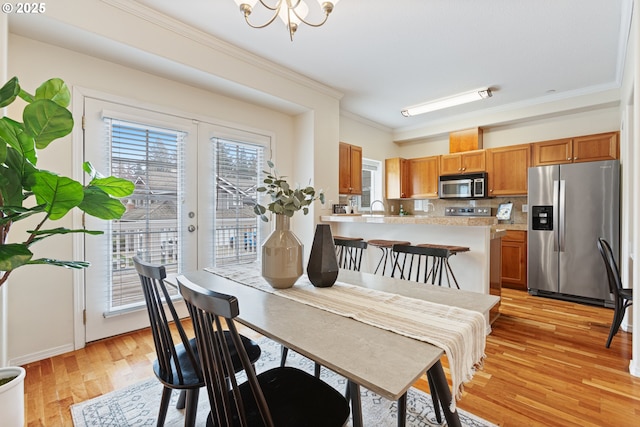 dining room featuring a notable chandelier, crown molding, and light wood-style floors