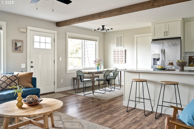 living room with hardwood / wood-style flooring, ceiling fan, and beam ceiling