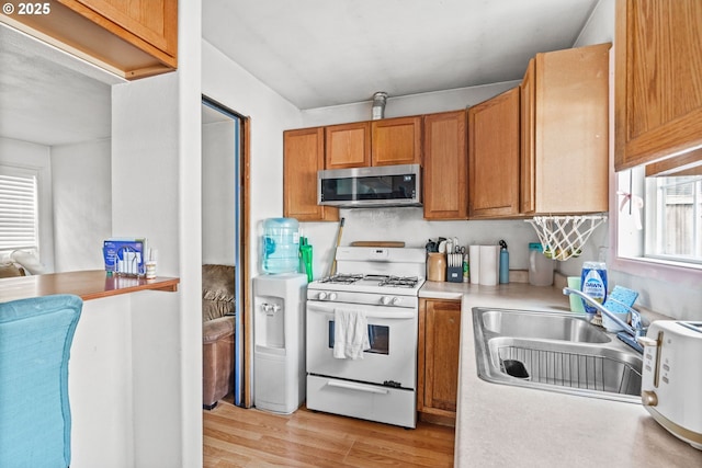 185 N Seneca Rd, Eugene, OR 97402 - kitchen featuring white gas stove, stainless steel microwave, light wood-style floors, light countertops, and brown cabinets