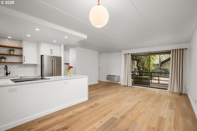 1919 NW Hoyt St Unit 104, Portland, OR 97209 - kitchen featuring high end refrigerator, black electric stovetop, a wall mounted air conditioner, decorative backsplash, and light wood finished floors