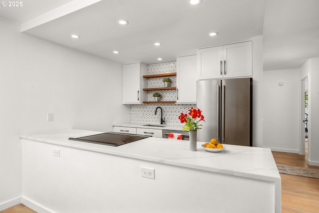 1919 NW Hoyt St Unit 104, Portland, OR 97209 - kitchen featuring high end fridge, black electric stovetop, open shelves, white cabinets, and light wood-style flooring