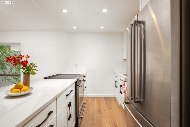 1919 NW Hoyt St Unit 104, Portland, OR 97209 - kitchen featuring high end appliances, recessed lighting, light wood finished floors, white cabinets, and light stone countertops
