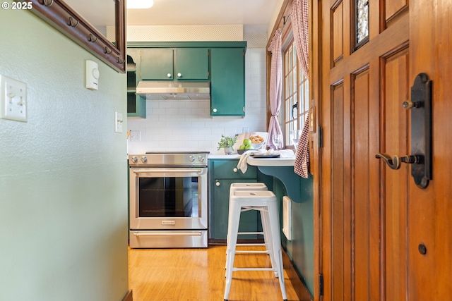 15787 SW Village Cir, Beaverton, OR 97007 - kitchen featuring electric stove, under cabinet range hood, green cabinets, light wood-style floors, and tasteful backsplash