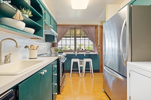 15787 SW Village Cir, Beaverton, OR 97007 - kitchen with green cabinets, stainless steel appliances, a sink, light wood-style flooring, and washer / dryer