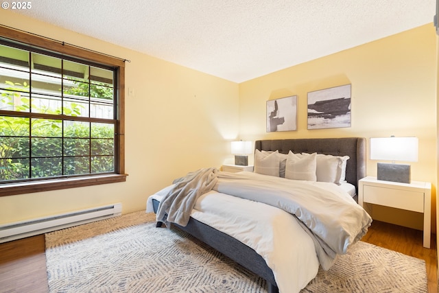 15787 SW Village Cir, Beaverton, OR 97007 - bedroom featuring wood finished floors, a baseboard heating unit, and a textured ceiling