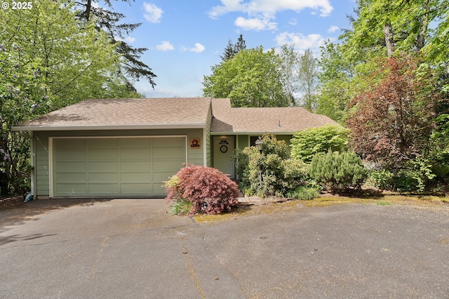 single story home with driveway, a shingled roof, and a garage