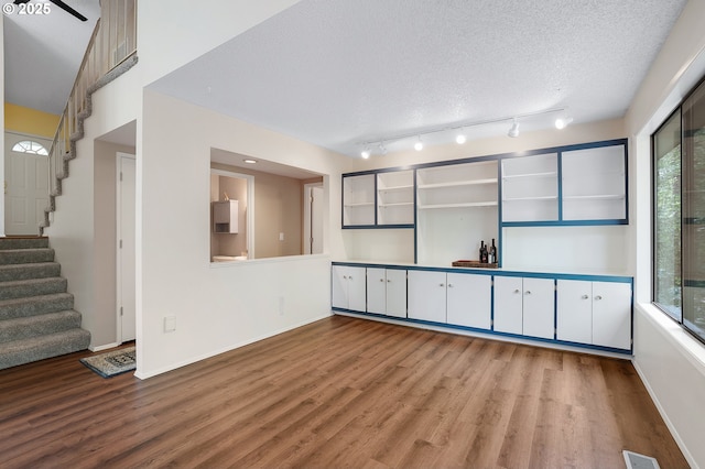 unfurnished room with baseboards, stairs, wood finished floors, and visible vents