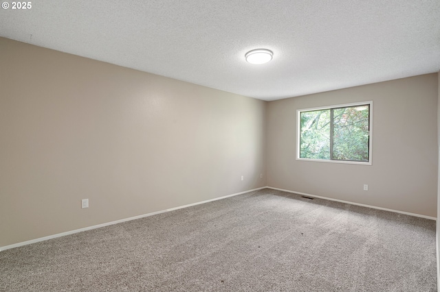 carpeted spare room with visible vents, a textured ceiling, and baseboards