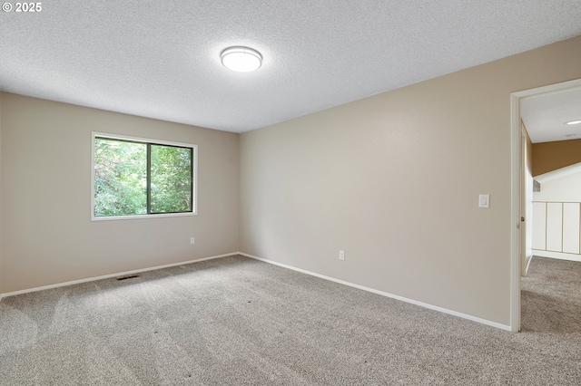 spare room with baseboards, carpet flooring, a textured ceiling, and visible vents