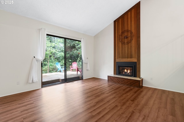 unfurnished living room with a large fireplace, baseboards, wood finished floors, and lofted ceiling