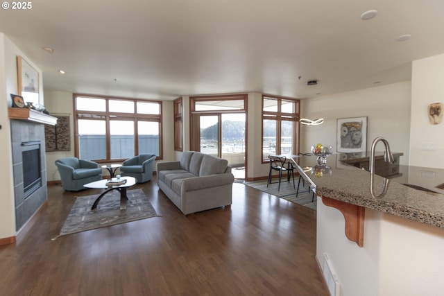 living room with dark wood finished floors, baseboards, and a tile fireplace