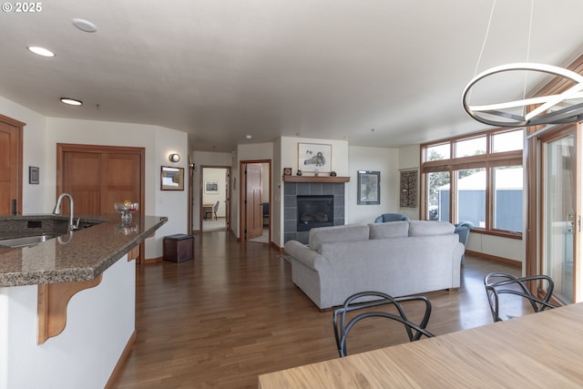 living area with dark wood finished floors, a fireplace, and baseboards