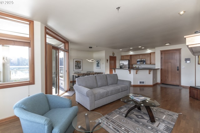 living area with recessed lighting, visible vents, baseboards, and wood finished floors