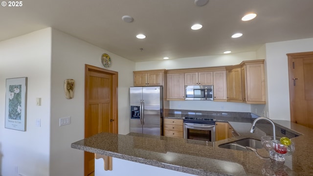 kitchen with recessed lighting, appliances with stainless steel finishes, a peninsula, and a sink