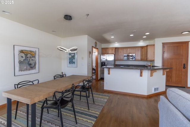 dining area with visible vents, dark wood-type flooring, recessed lighting, stacked washer / drying machine, and baseboards