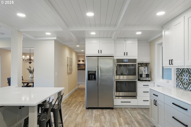 kitchen featuring a kitchen bar, light wood-type flooring, white cabinets, and appliances with stainless steel finishes