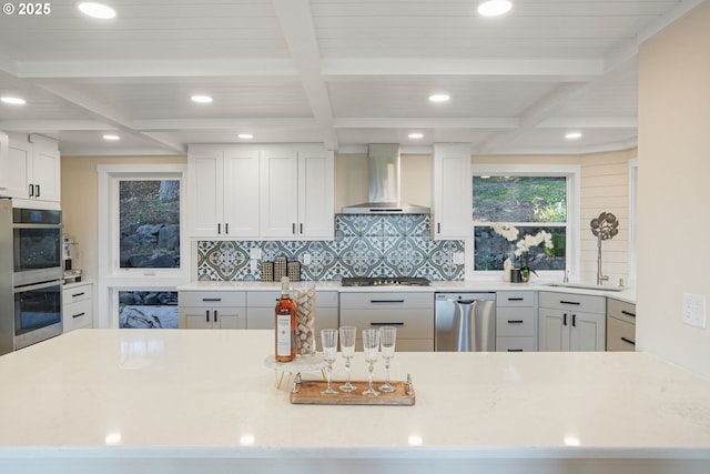 kitchen featuring white cabinets, appliances with stainless steel finishes, and wall chimney range hood