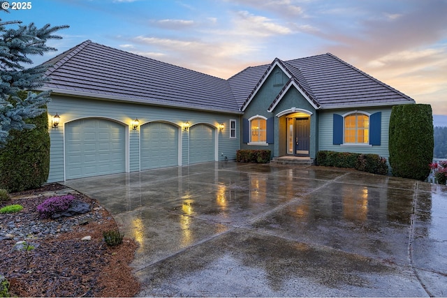 ranch-style home with a tile roof, an attached garage, and concrete driveway