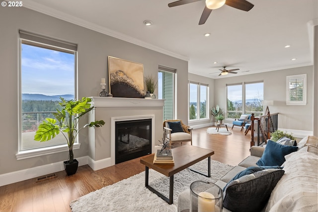 living area with crown molding, wood finished floors, and visible vents