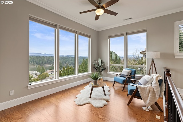 sitting room with wood finished floors, visible vents, and ornamental molding