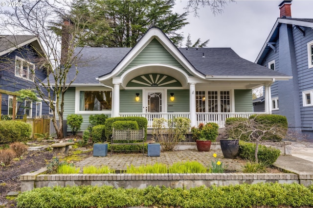 bungalow with covered porch and a shingled roof