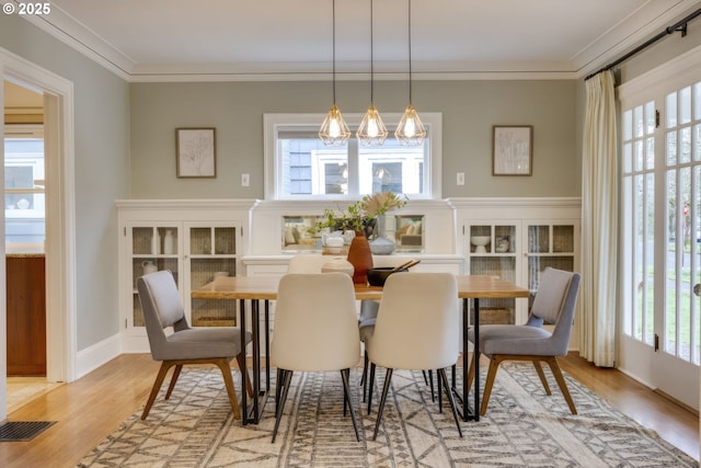 dining room featuring visible vents, a healthy amount of sunlight, crown molding, and light wood finished floors