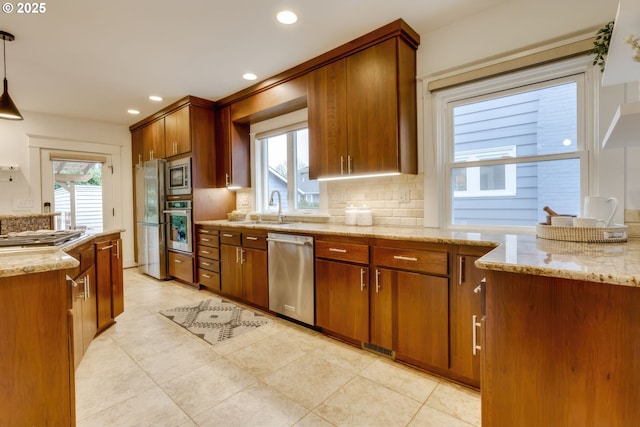 kitchen with stainless steel appliances, plenty of natural light, backsplash, and light stone countertops