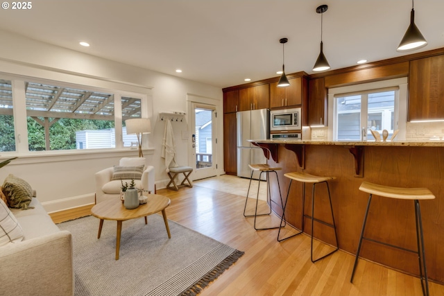 kitchen with decorative backsplash, a healthy amount of sunlight, light wood finished floors, and stainless steel appliances