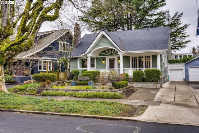 view of front of house with an outbuilding, covered porch, a chimney, and a shingled roof