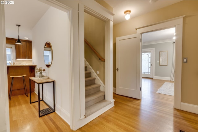 stairway with baseboards, wood finished floors, and crown molding