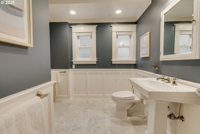 bathroom featuring a wainscoted wall, marble finish floor, toilet, and ornamental molding