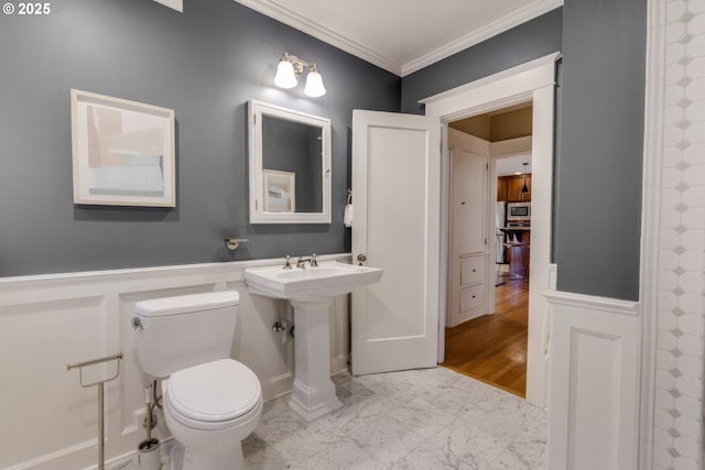 full bath featuring a wainscoted wall, ornamental molding, a decorative wall, toilet, and marble finish floor