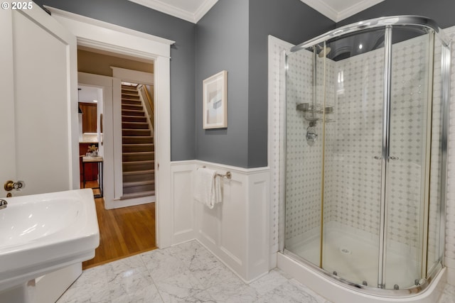 full bath featuring a wainscoted wall, marble finish floor, a shower stall, and ornamental molding