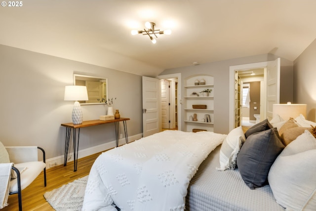 bedroom featuring baseboards, an inviting chandelier, wood finished floors, and vaulted ceiling