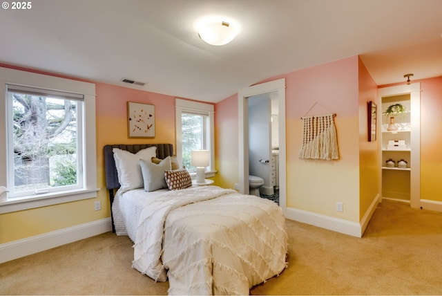 bedroom with baseboards, visible vents, and light carpet