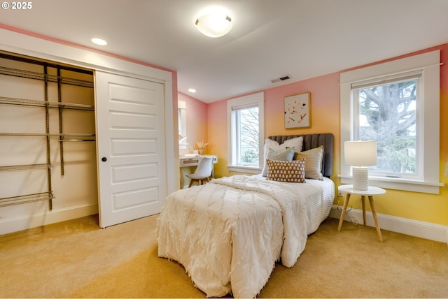 bedroom with a closet, recessed lighting, light colored carpet, and baseboards