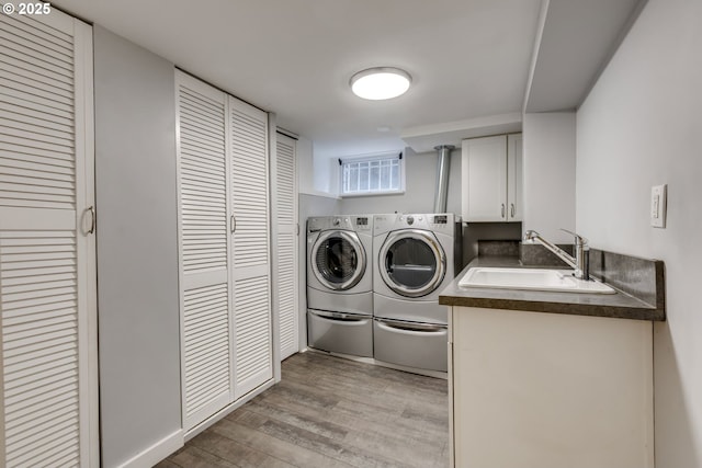 laundry room with washer and clothes dryer, light wood-style flooring, cabinet space, and a sink