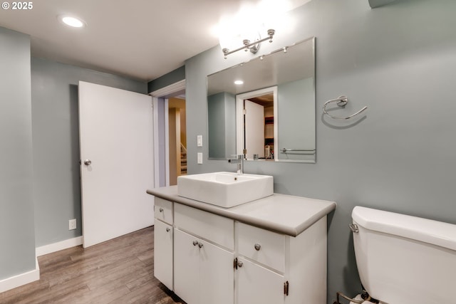 bathroom featuring vanity, wood finished floors, baseboards, recessed lighting, and toilet