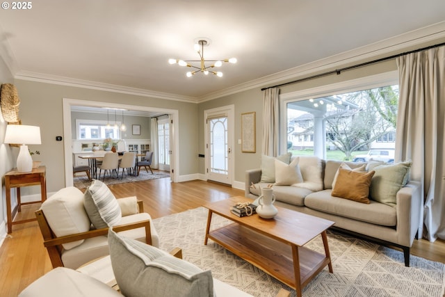 living area featuring crown molding, light wood-style flooring, and a chandelier